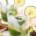 two glasses of Caipirinha recipe with ice, limes, and straws