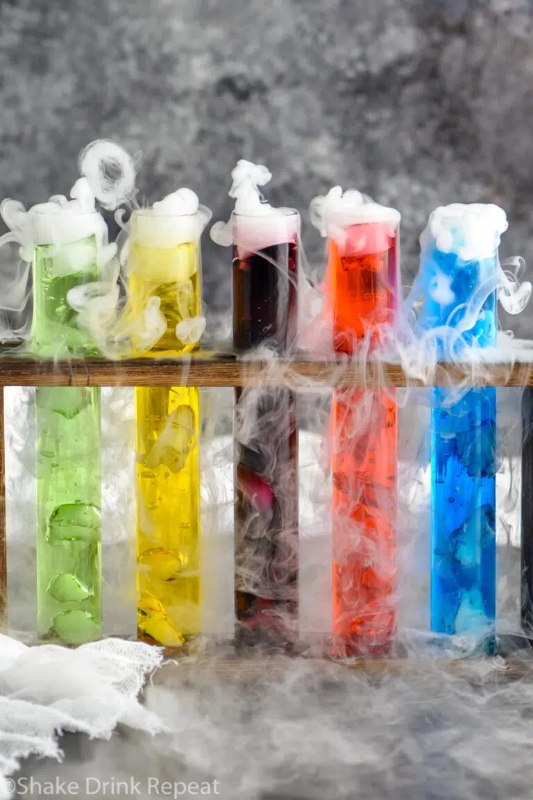 three test tubes of mad scientist shots in a wooden holder with dry ice causing smokey appearance