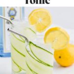 pinterest graphic for cucumber lemon gin and tonic. Text says "the best cucumber lemon gin and tonic shakedrinkrepeat.com" Image shows two glasses of cucumber lemon gin and tonic with cucumber and lemon slice garnish and straw. Cucumber slices, lemons, and bottle of gin surrounding.